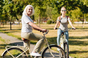 Fototapeta premium Joyful senior woman riding a bicycle with her granddaughter
