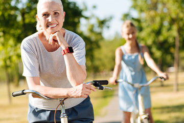 Joyful senior woman riding bicycle with her granddaughter