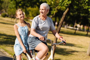 Delighted positive senior woman riding a bicycle