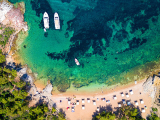 Obraz na płótnie Canvas Aerial view of sandy beach with sunbathing tourists and yachts