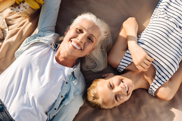 Top view of smiling woman and her granddaughter lying in the park