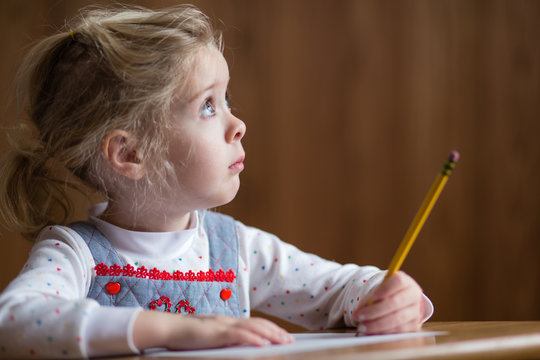 Preschool girl paying attention while doing homework