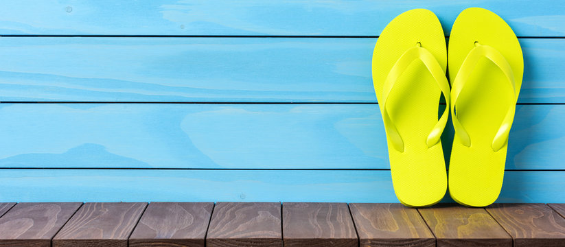 Green flip flops on wooden background. Close up
