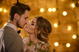 Stylish hipster wedding couple in romantic loft decorations at night kiss portrait