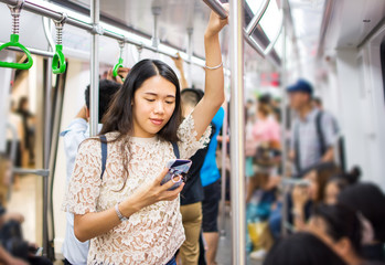 Asian girl using phone on subway