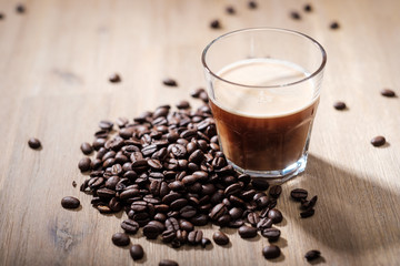Fresh coffee in a glass with coffee beans on a wood table