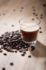 Fresh coffee in a glass with coffee beans on a wood table