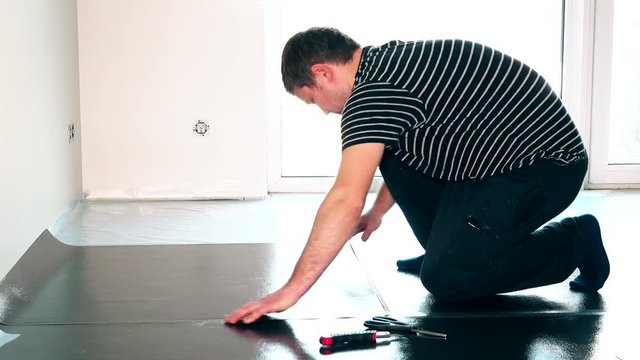 careful male worker man laying underlay for the laminate flooring installation