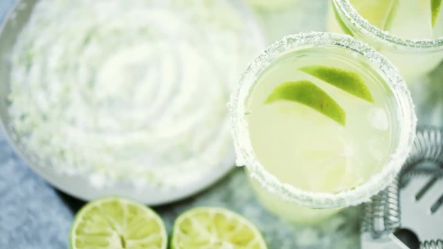 Key lime margarita garnished with fresh lime and salt in mason jar on metal tray