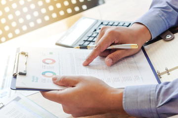 business man analyzing graph and chart document on office desk