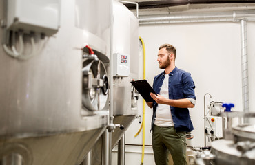 man with clipboard at craft brewery or beer plant