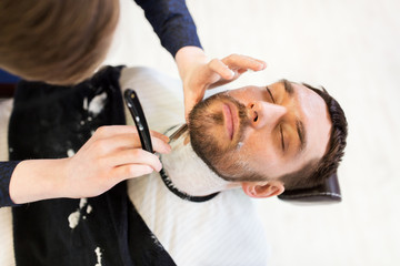 man and barber with straight razor shaving beard