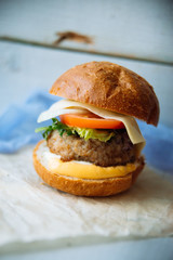 Tasty burger with beef with spinach and blue cheese served on a small board on a wooden background.