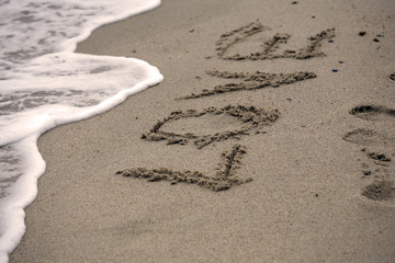 Love message on beach - feelings and symbol concept; selective focus background.