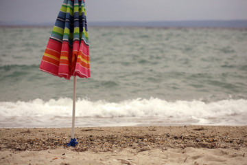 Closed umbrella on beach; selective focus background.