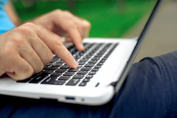 Close-up shot of handsome man's hands touching laptop computer's screen.