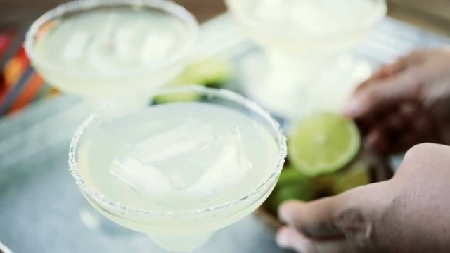 Key lime margarita garnished with fresh lime and salt in margarita glass on metal tray