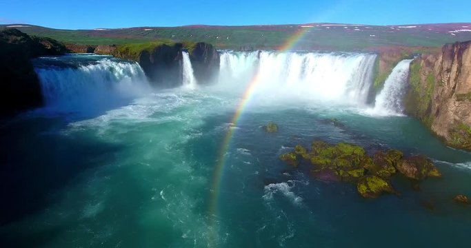 Horseshoe Waterfall With Rainbow Emptying into Wide Blue River - Godafoss Falls in Iceland