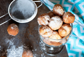 Homemade small donuts with powdered sugar in the glass