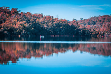Small boat with two fishermen on smooth river water surface. Native Australian Landscape.