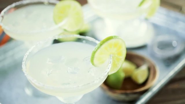 Key lime margarita garnished with fresh lime and salt in margarita glass on metal tray