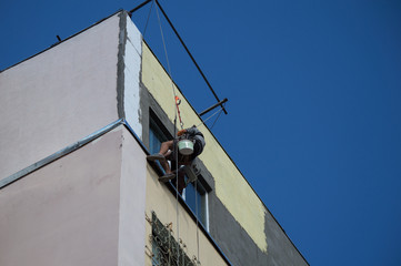 Industrial alpinism. The man in the outfit carries out work on the facade of the house