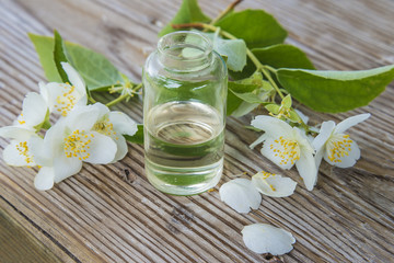 jasmine essential oil and flowers on old wooden background