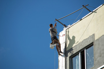 Industrial alpinism. The man in the outfit carries out work on the facade of the house