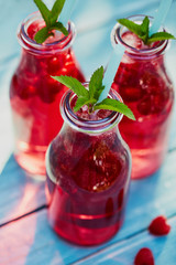 Three glasses of lemonade with raspberries and mint leaves, top view