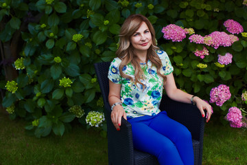 Woman is sitting on chair in garden on grass