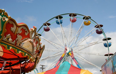 Fair carnival rides and tent top against blue sky. - obrazy, fototapety, plakaty