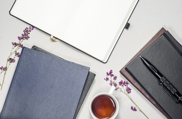 Flat composition cup with tea, books, pads, pen, purple dry flowers