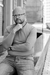 Fototapeta premium Portrait of mature simple hipster man, with red beard walk at the European city and thinking about something