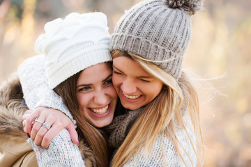 Two girls friends with hats hugging. Autumn.