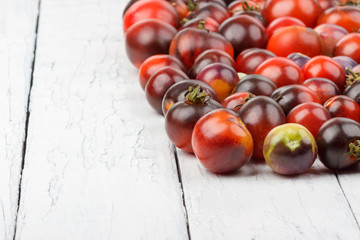 Different tomatoes on the white wooden background