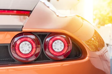 Fototapete Schnelle Autos Back of an orange sport luxury car in sunset