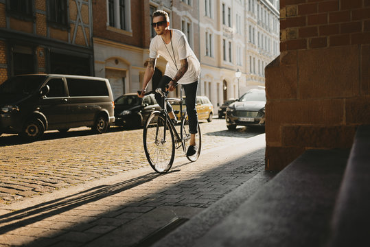 Radfahrer f&auml;hrt mit Singlespeed bei Sonnenuntergang durch die Stadt