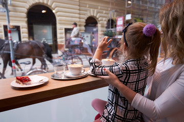 Young woman and little girl making photos through window