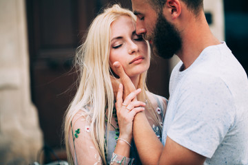 Obraz na płótnie Canvas Blonde girl and Hipster handsome man with beard hugging and kissing on the city streets