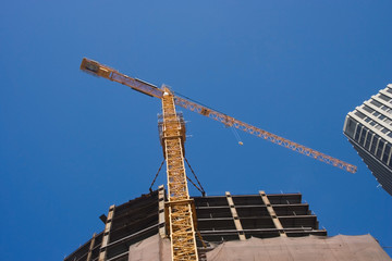 Naklejka premium Tower crane and building construction against blue sky.