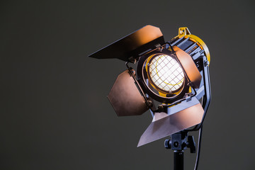 Floodlight with halogen lamp and Fresnel lens on a gray background. Lighting equipment for...