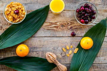 Summer fruity breakfast. Muesli, oranges, cherry on wooden table background top view copyspace