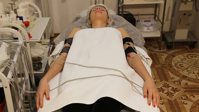 Woman receiving an electro therapy at the health center.Attractive female patient receiving electro threrapy beauty treatment.An attractive girl with electrodes on his hands received electrical