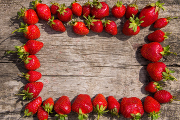 Frame of fresh red strawberries on wooden tabletop with copy space Top view