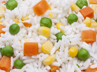 Closeup of rice texture with corn, carrot and pea grains