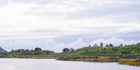 Des maisons dans la prairie, au bord d'un fjord