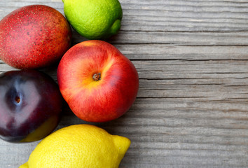 Fresh ripe organic fruits on old wooden table.Lemon,lime,plum and mango and peach.Diet,healthy food,raw food concept.Selective focus.