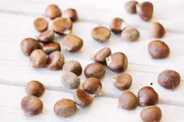 Fresh raw chestnuts on white wooden surface.