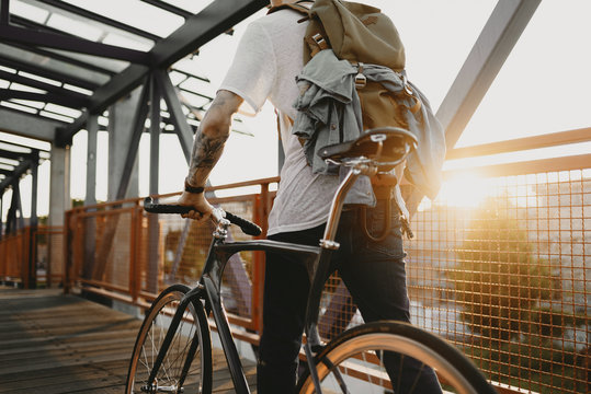Radfahrer f&auml;hrt mit Singlespeed bei Sonnenuntergang durch die Stadt