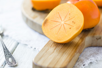 Half of persimmon fruit on wooden board.